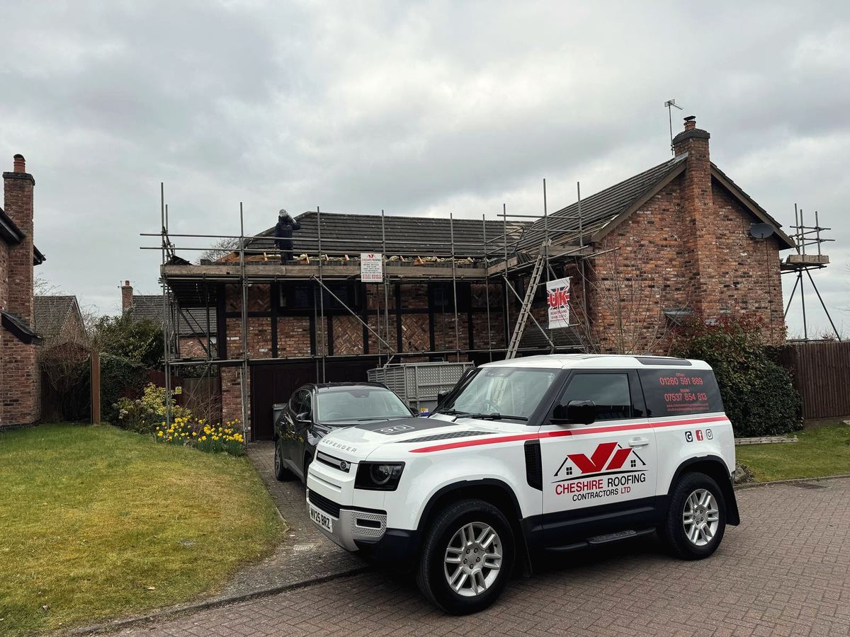 Cheshire Roofing Contractors branded Defender outside a stone house with scaffolding during a roofing project