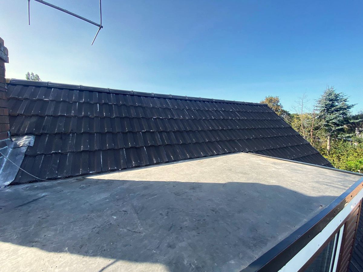 Seamless flat roof on extension below a pitched tile roof
