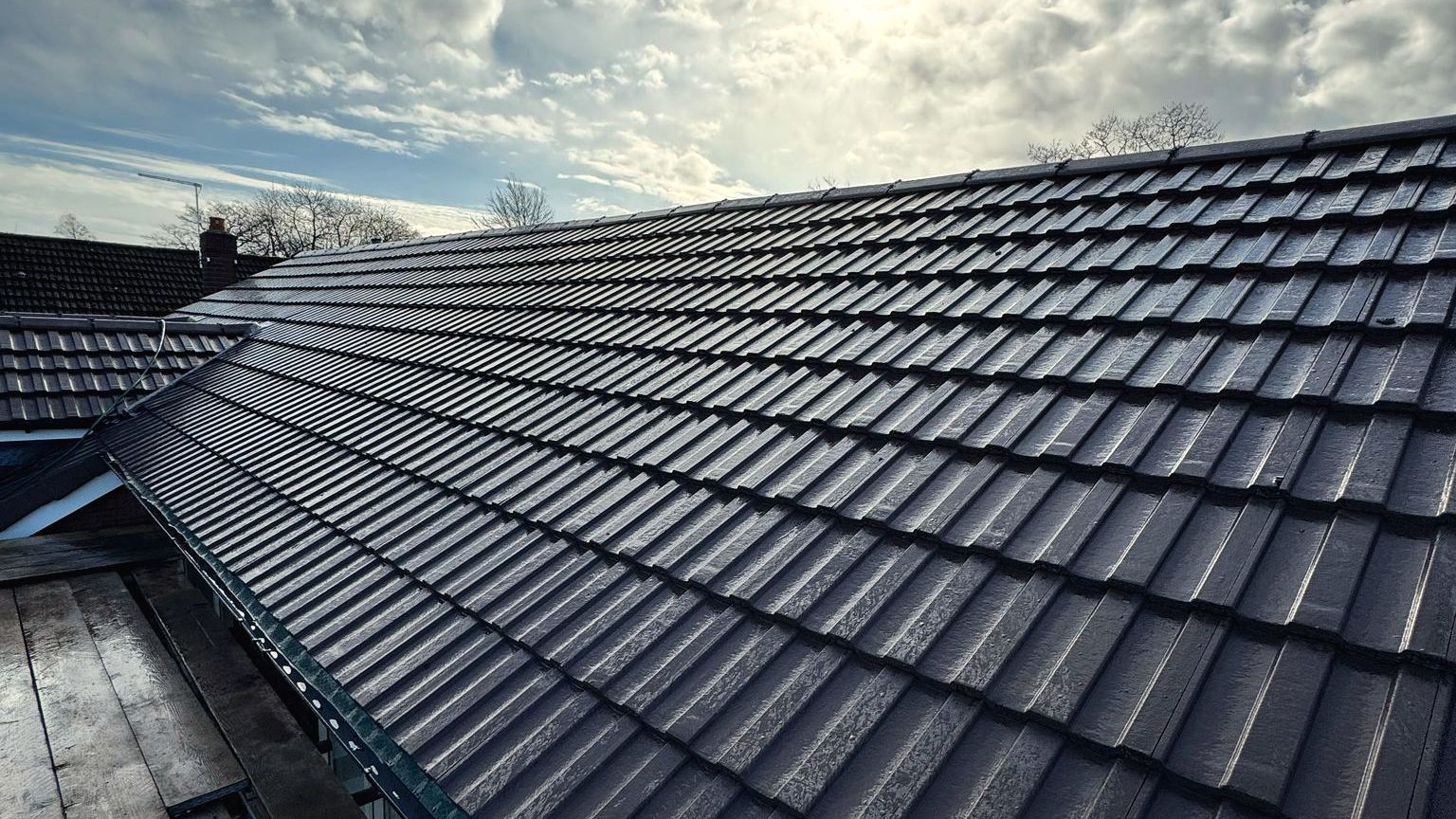 Newly installed dark tile roof in Cheshire under a dramatic sky, completed by Cheshire Roofing Contractors