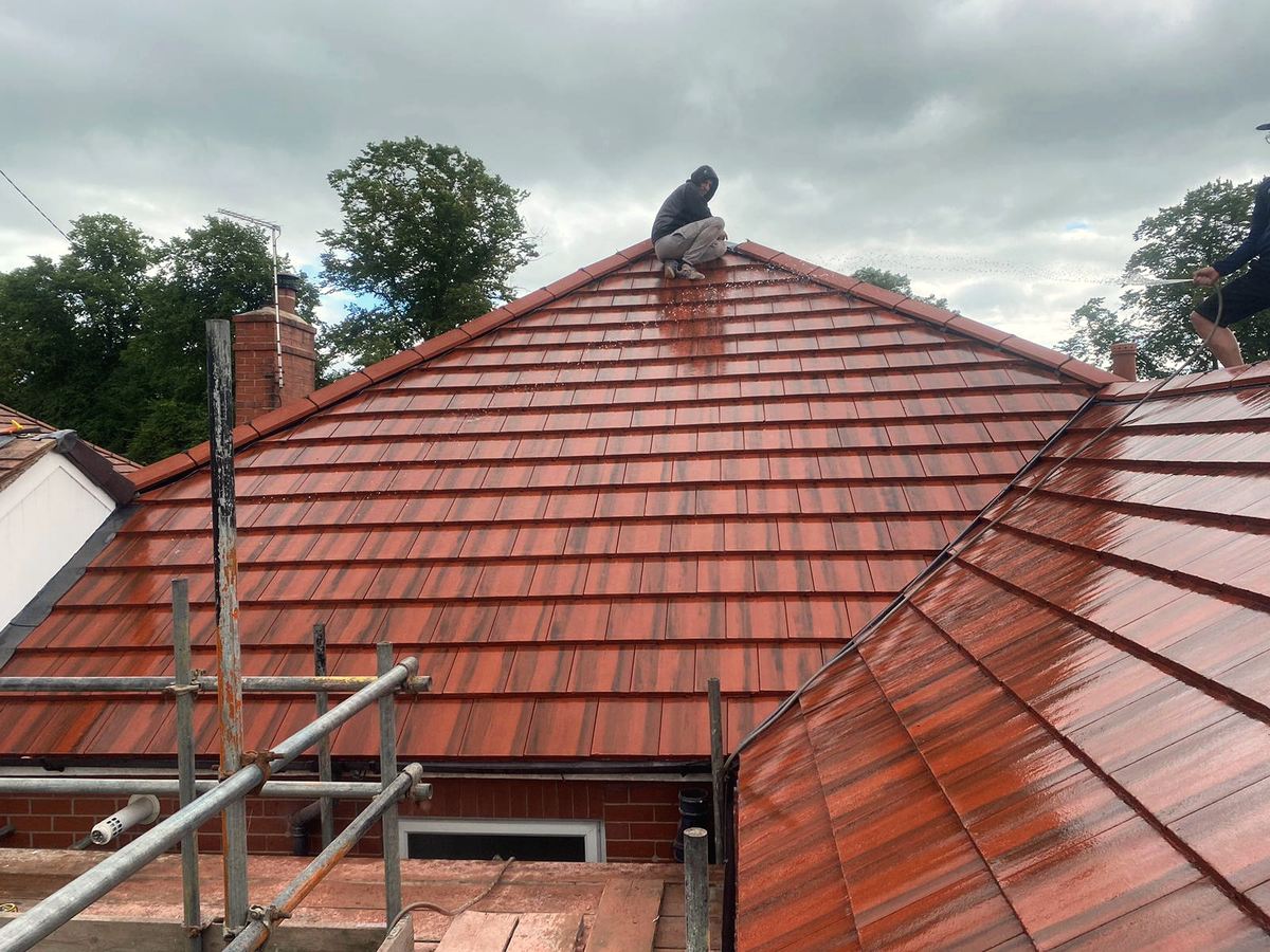 Roofer finishing a new red tile roof at the ridge