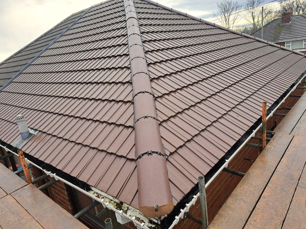 Brown tile roof with ridge line being completed